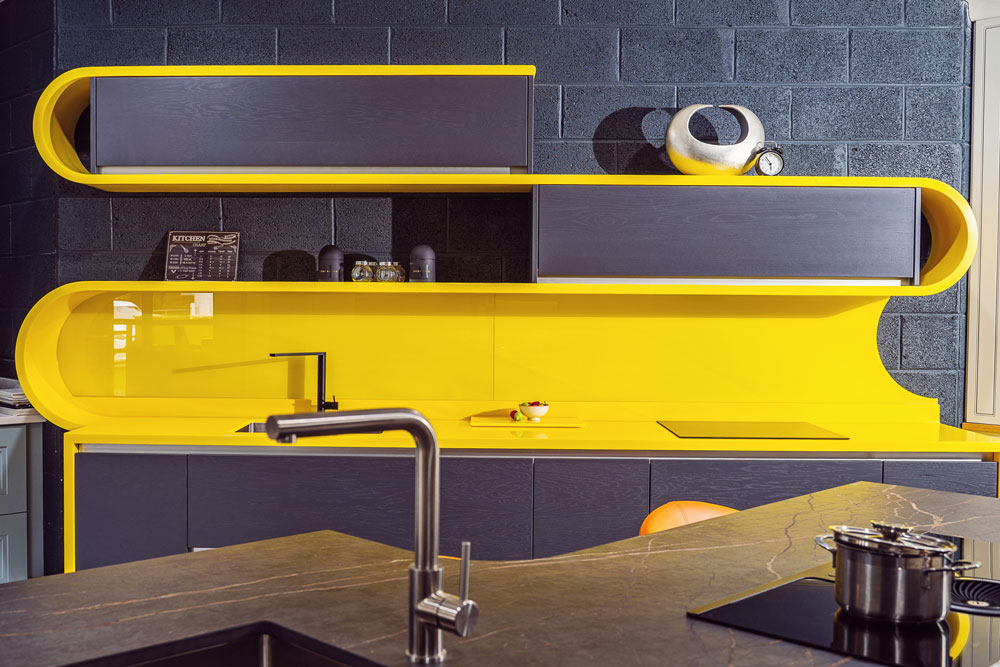 Modern kitchen design with shaped yellow colour glass kitchen splasbhack